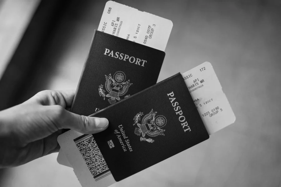 Pessoa segurando dois passaportes com bilhetes de avião, simbolizando viagens corporativas e mobilidade internacional.